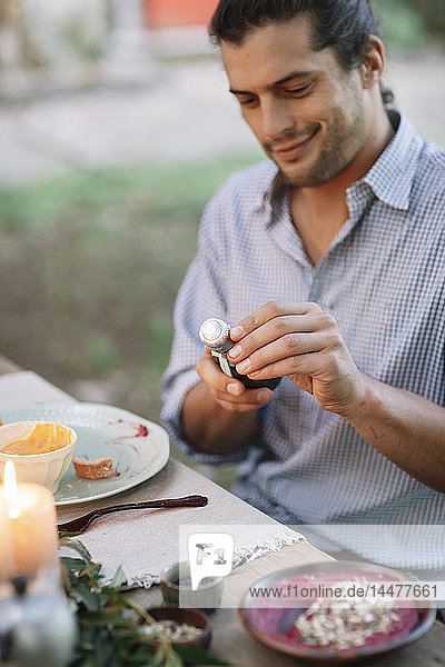 Man opening a bottle of sparkling wine at garden table