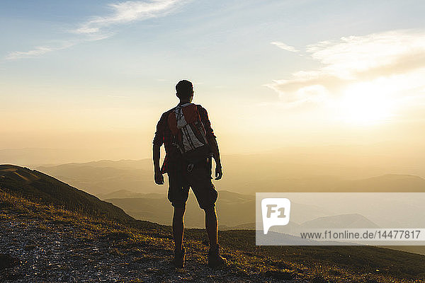 Italy  Monte Nerone  hiker on top of a mountain looking at panorama at sunset