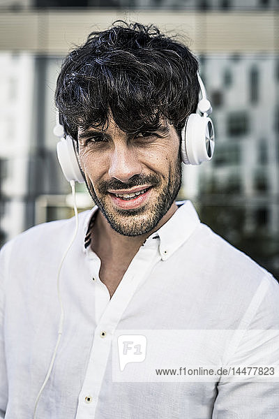 Portrait of young man wearing headphones in the city