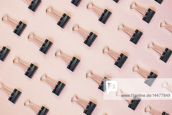 Black paper clips against pink background