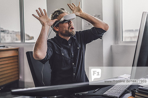 Grafikdesigner  der eine VR-Brille trägt  die Zunge herausstreckt und sich schelmisch darüber lustig macht