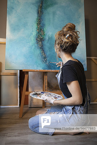 Junge Frau malt in ihrem Atelier