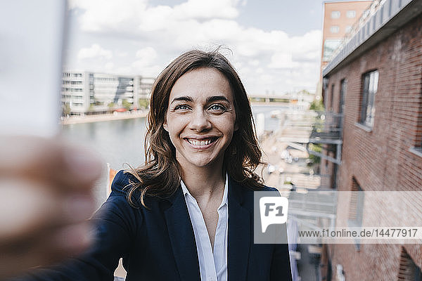 Happy businesswoman taking a smartphone selfie