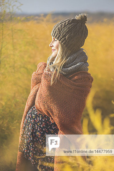 Lächelnde schwangere Frau mit geschlossenen Augen genießt den Sonnenschein