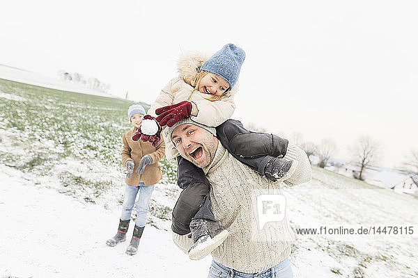 Verspielter Vater trägt Tochter huckepack in Winterlandschaft