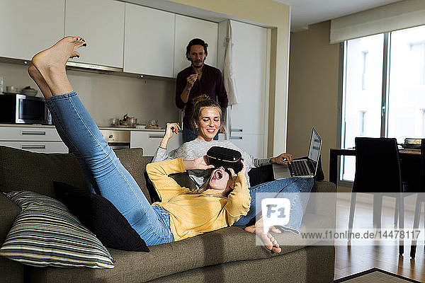 Freunde sitzen auf der Couch im Wohnzimmer  spielen mit VR-Brille
