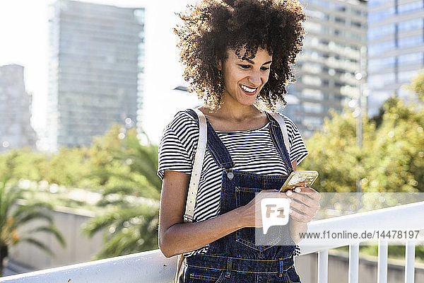 Junge Frau steht auf einer Brücke und benutzt ein Smartphone