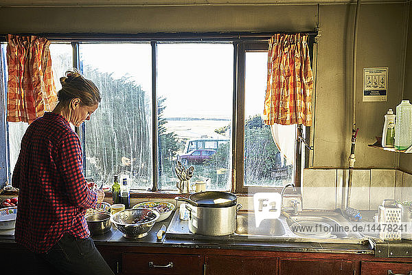 Frau steht in Küche und bereitet Essen vor