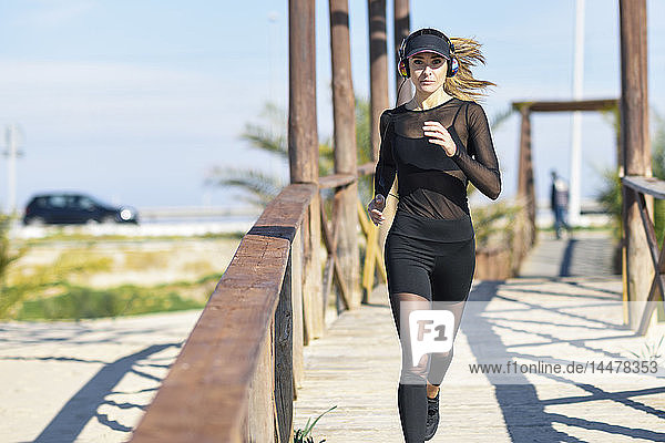 Sportliche Frau läuft auf Holzbrücke