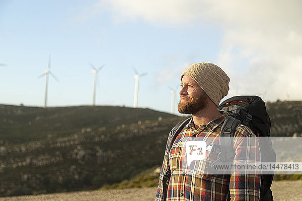 Spanien  Andalusien  Tarifa  lächelnder Mann auf einer Wanderung mit Windturbinen im Hintergrund