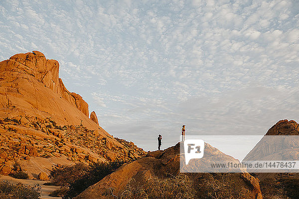 Namibia  Spitzkoppe  Ehepaar steht bei Sonnenuntergang auf einem Felsen