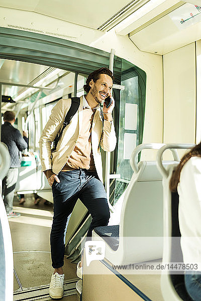 Lachender Mann am Telefon in der Strassenbahn