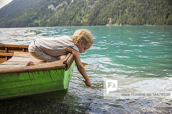 Österreich  Kärnten  Weissensee  Mädchen im Ruderboot  das einen Stock ins Wasser wirft