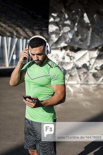 Sportlicher Mann beim Training  mit Smartphone und Kopfhörern