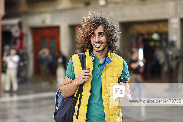 Spain  Granada  portrait of smiling young tourist with backpack discovering the city