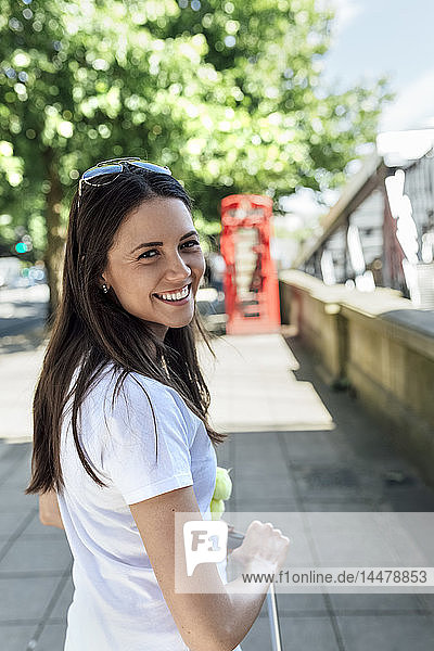 UK  London  Porträt einer lächelnden jungen Frau auf der Straße