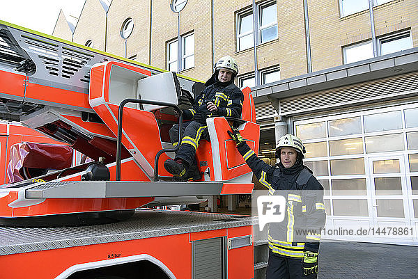 Porträt von zwei Feuerwehrleuten bei einer Übung am Löschfahrzeug