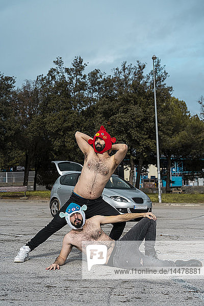 Gay couple wearing animal hats posing at car park