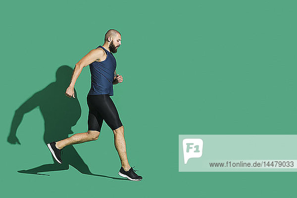 Bärtiger Mann joggt vor grünem Hintergrund