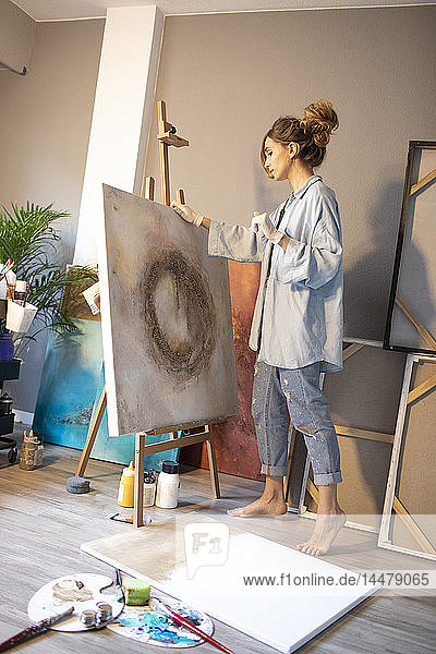 Junge Frau betrachtet fertige Gemälde in ihrem Atelier