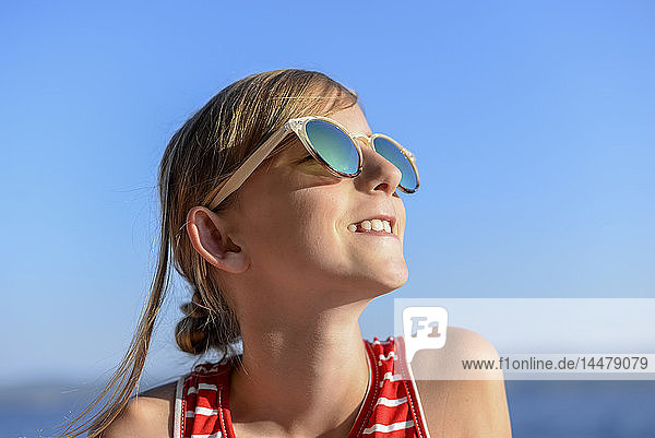 Kroatien  Lokva Rogoznica  Porträt eines sonnenbadenden Mädchens am Strand mit Sonnenbrille