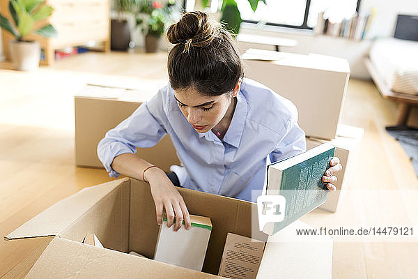 Young woman unpacking cardboard box in new apartment