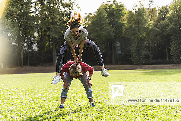 Enkelin springt in einem Park über ihre Großmutter