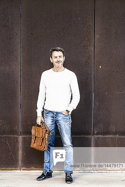 Mature man standing in front of steel facade  holding briefcase