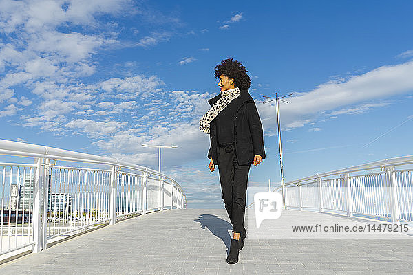 Spanien  Barcelona  lächelnde Frau in Schwarz gekleidet beim Überqueren einer Brücke