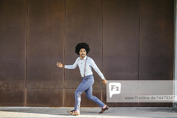 Porträt eines tanzenden Mannes vor einer rostigen Metallwand
