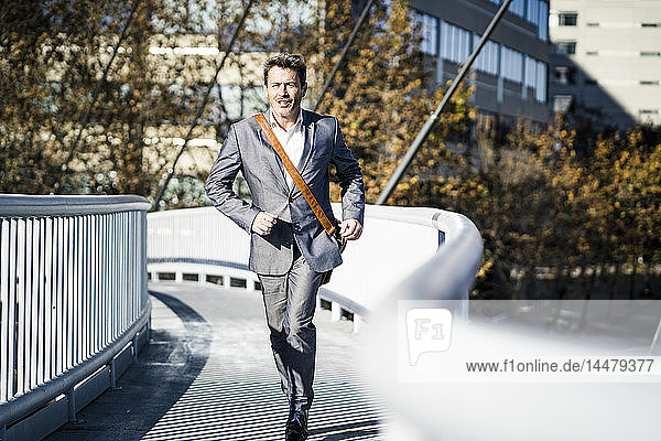 Businessman wearing full suit  running on a bridge