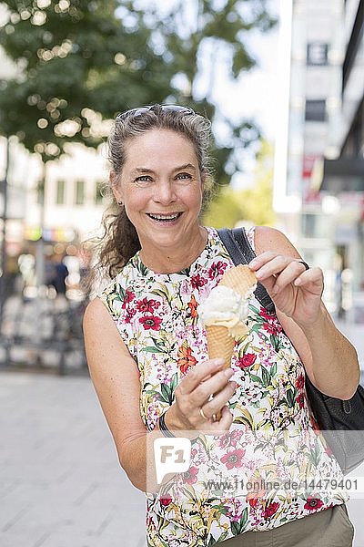 Porträt einer lächelnden reifen Frau mit Eistüten in der Stadt