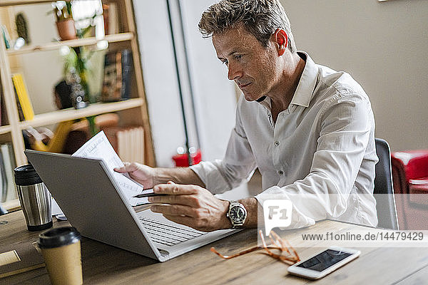 Fokussierter Geschäftsmann mit Laptop am Schreibtisch