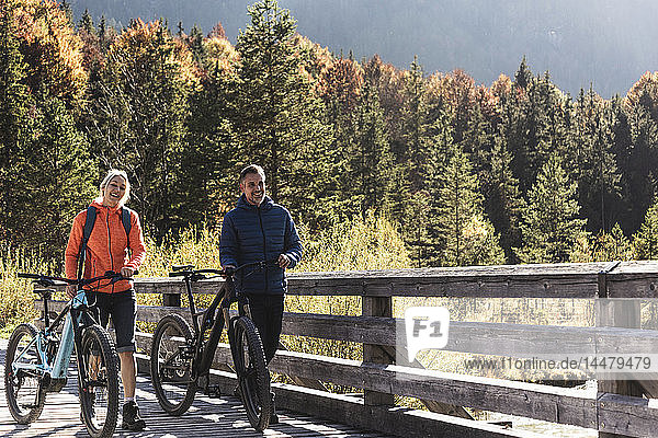 Austria  Alps  couple with mountain bikes crossing a bridge
