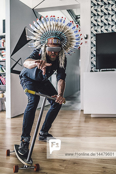 Mann mit indischem Kopfschmuck und VR-Brille im Büro  mit Kickroller