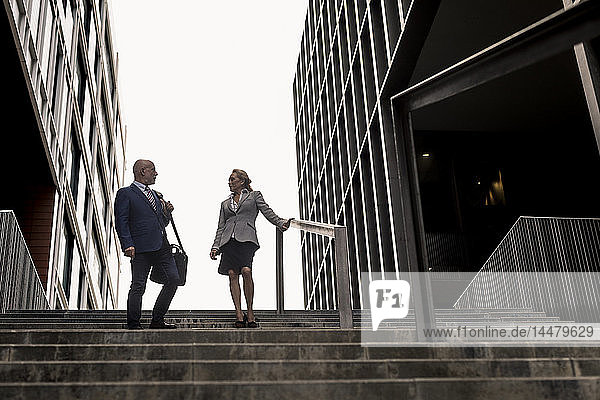 Leitender Geschäftsmann und Geschäftsfrau im Gespräch auf einer Treppe in der Stadt
