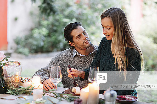 Romantic couple having a candlelight meal at garden table