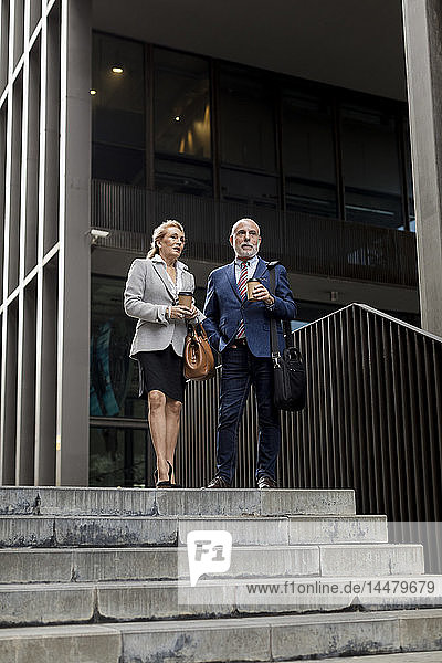 Leitender Geschäftsmann und Geschäftsfrau im Gespräch vor einem Bürogebäude in der Stadt