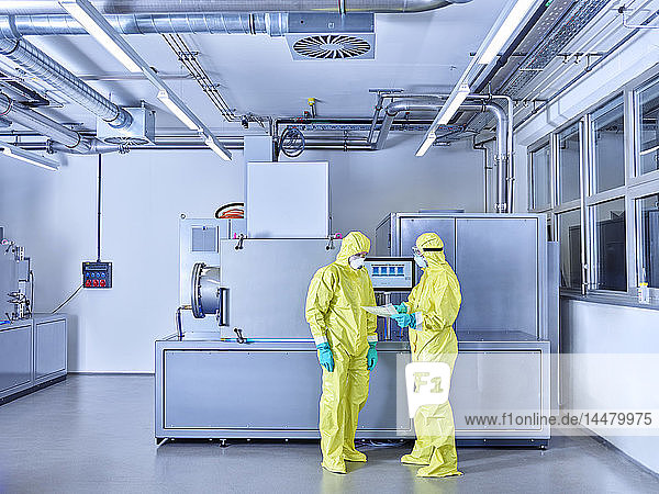 Chemiker  die im Industrielabor arbeiten und im Reinraum Schutzkleidung tragen