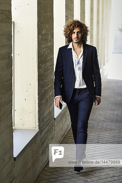 Portrait of young fashionable businessman with curly hair wearing blue suit