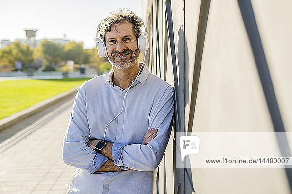 Portrait of smiling mature man listening to music with headphones