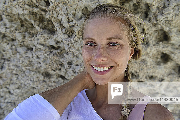 Porträt einer lächelnden blonden Frau mit felsigem Hintergrund