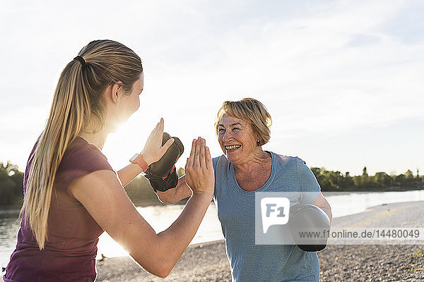 Grandmother doing boxing training with her graddaughter at the river