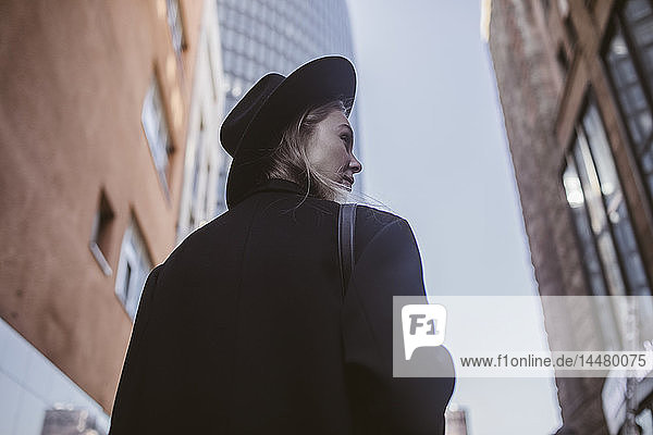 Woman with hat dressed in black walking in the city