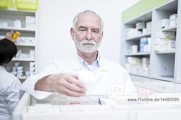 Pharmacist taking medicine from cabinet in pharmacy