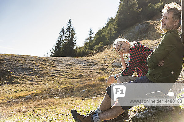 Wanderndes Ehepaar sitzt vor der Berghütte und macht eine Pause