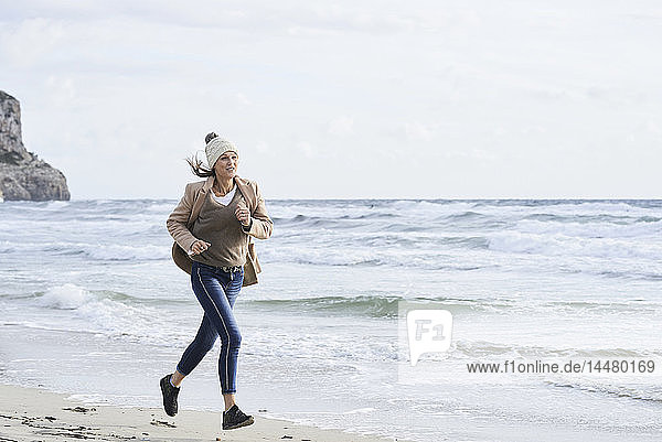 Spanien  Menorca  ältere Frau  die im Winter am Strand joggt