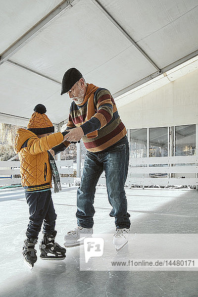 Grandfather and grandson on the ice rink  ice skating