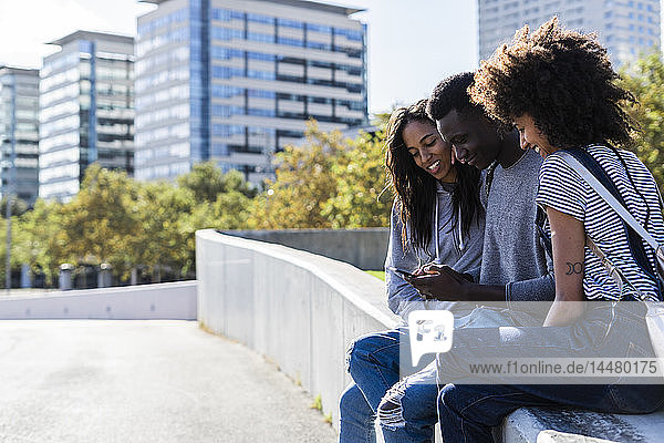 Drei Freunde verbringen Zeit in der Stadt und benutzen ein Smartphone
