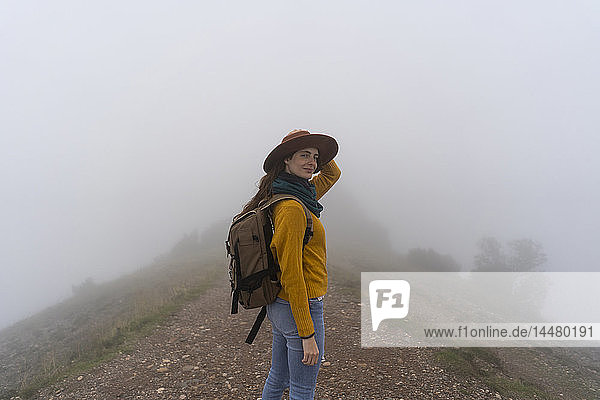 Woman hiking in the fog  standing on a mountain path